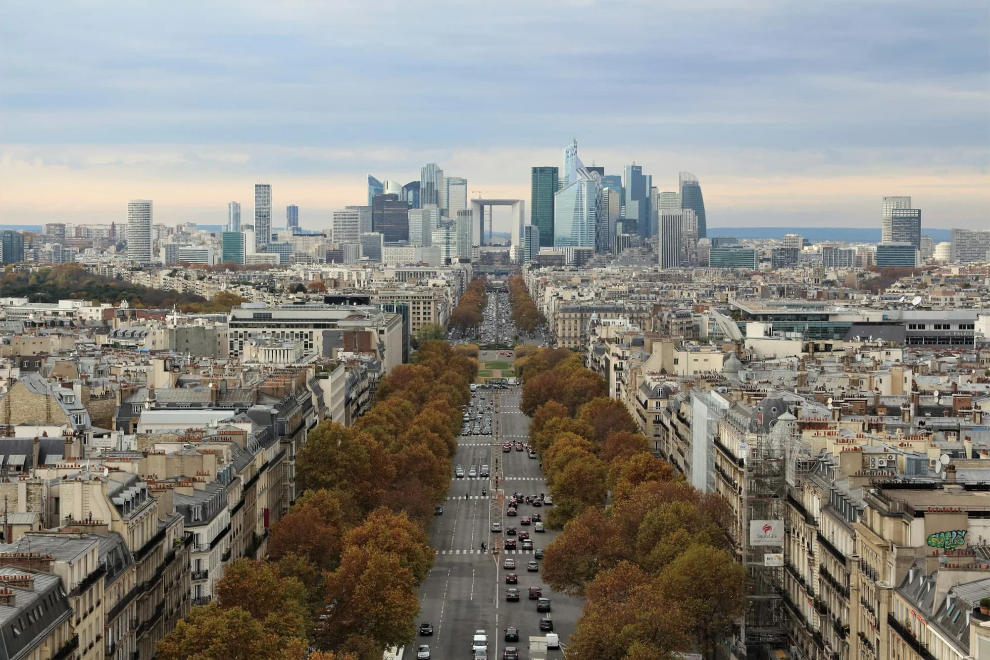 Perspective parisienne bordée d'immeubles haussmanniens menant vers les tours du quartier d'affaires de La Défense